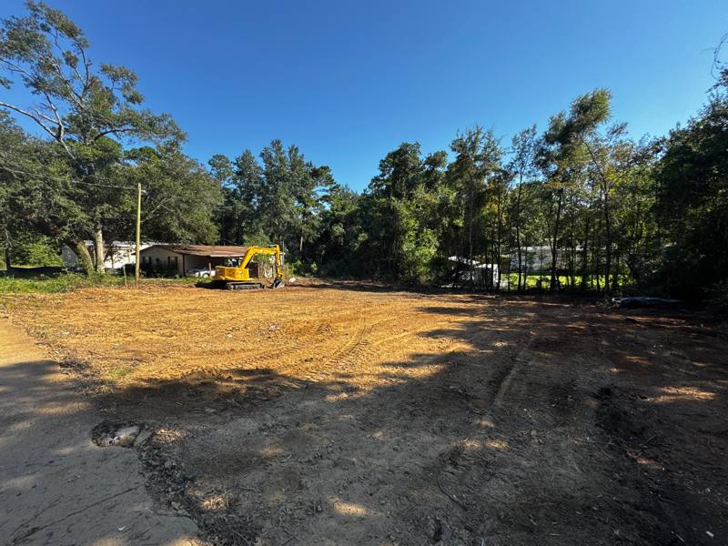 Cleared lot with a yellow mini excavator