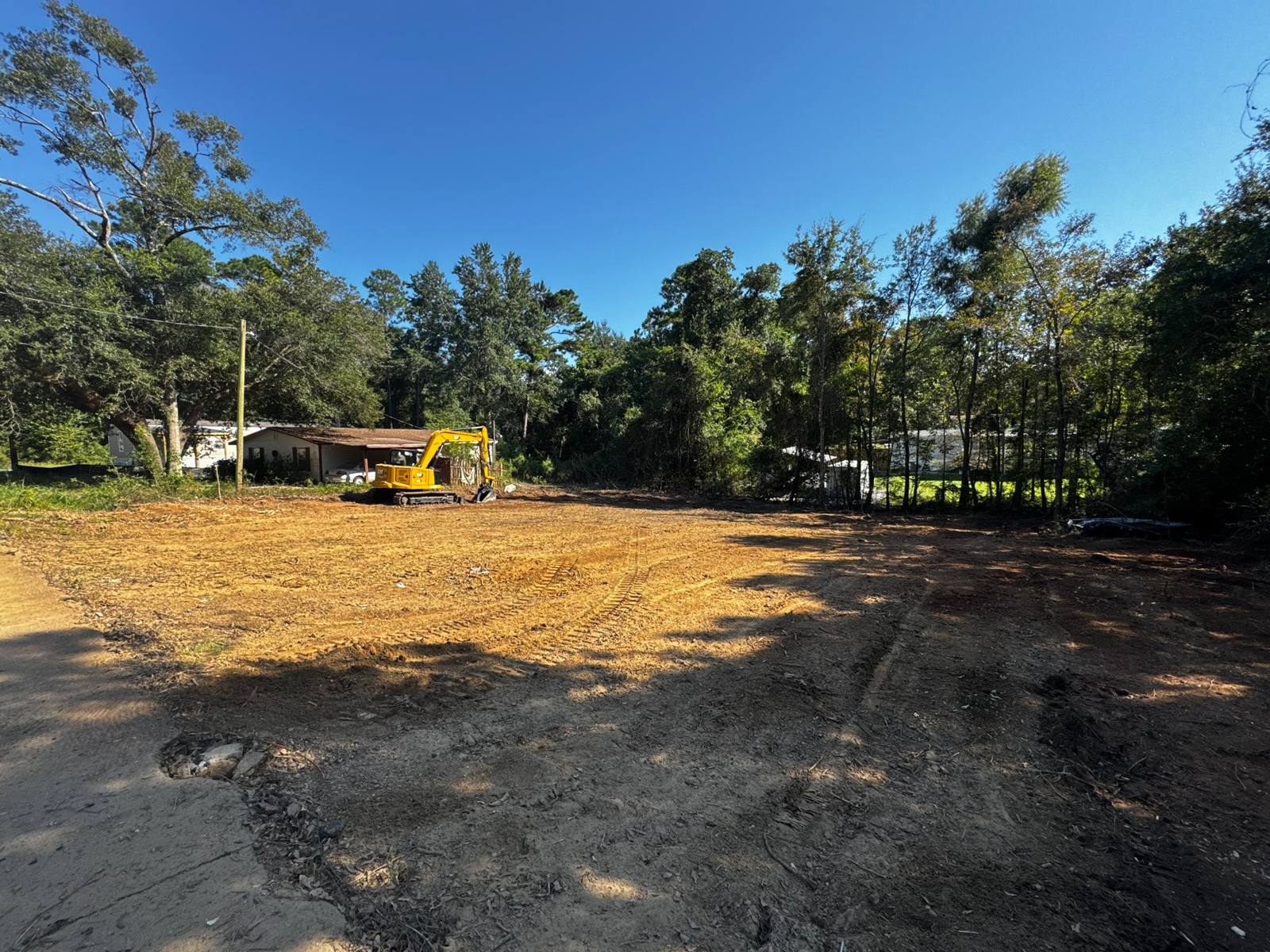 Freshly cleared lot with a yellow excavator on site